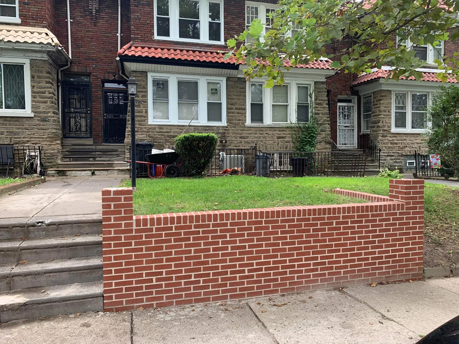 After: Failing block retaining wall refaced in red brick, with a soldier course cap and end piers