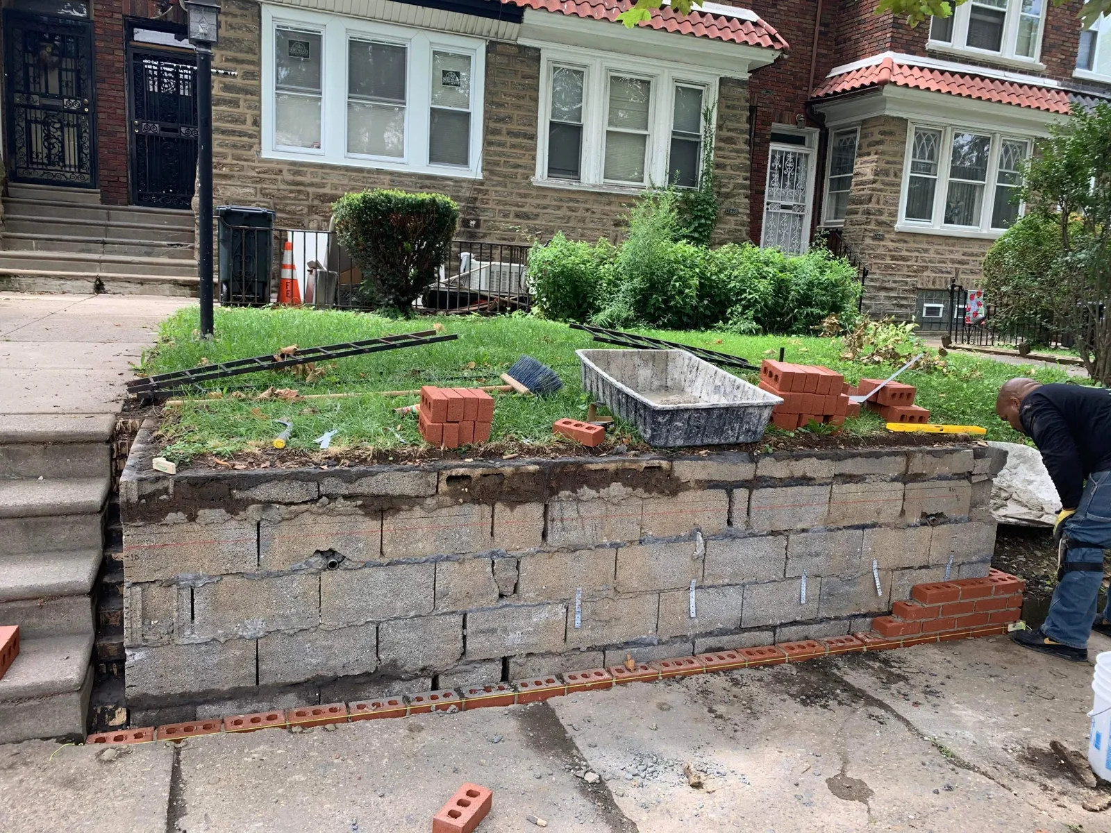 Before: Failing block retaining wall refaced in red brick, with a soldier course cap and end piers