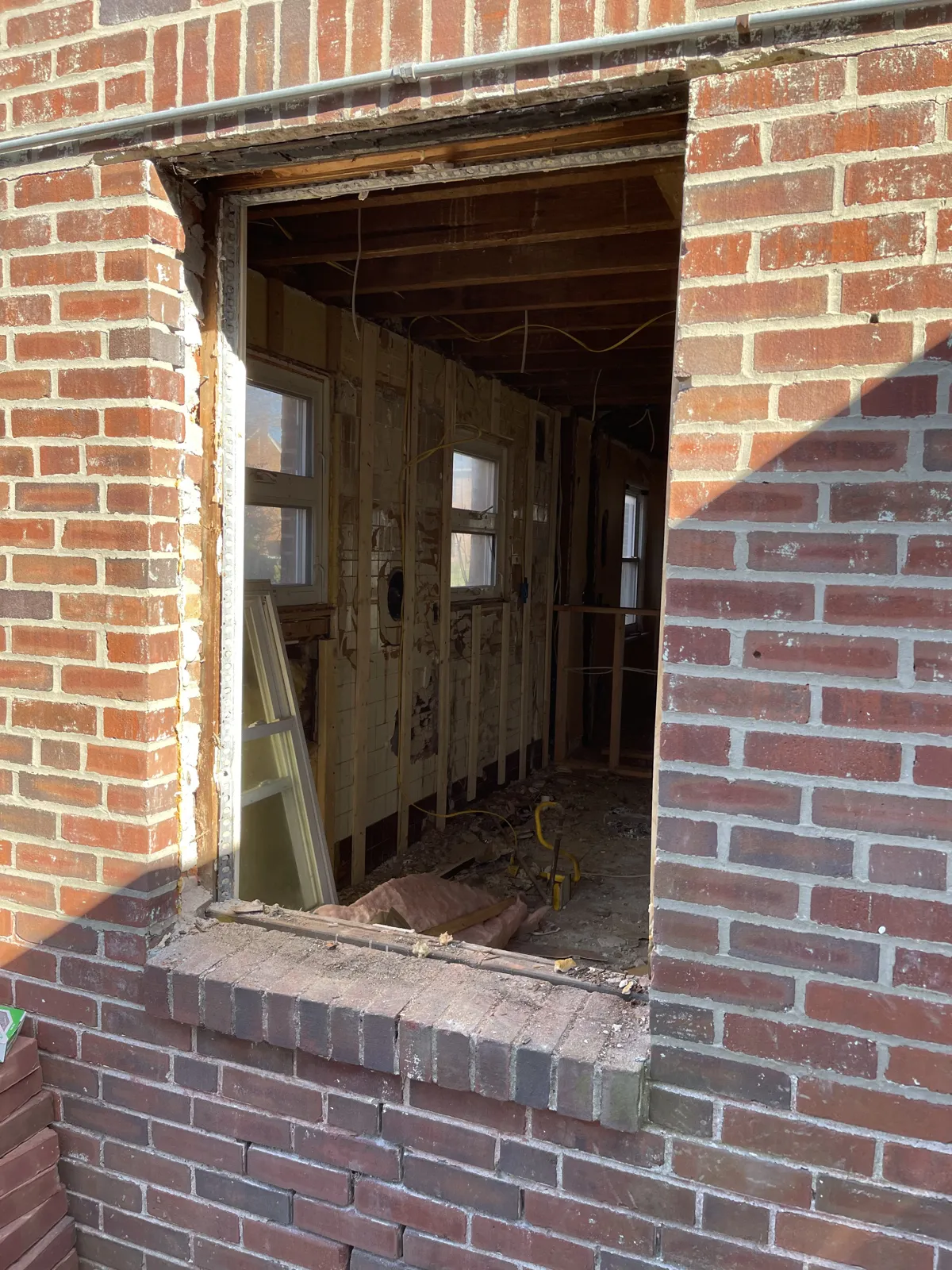 Before: Window opening infilled with brick and mortar matched to the existing wall